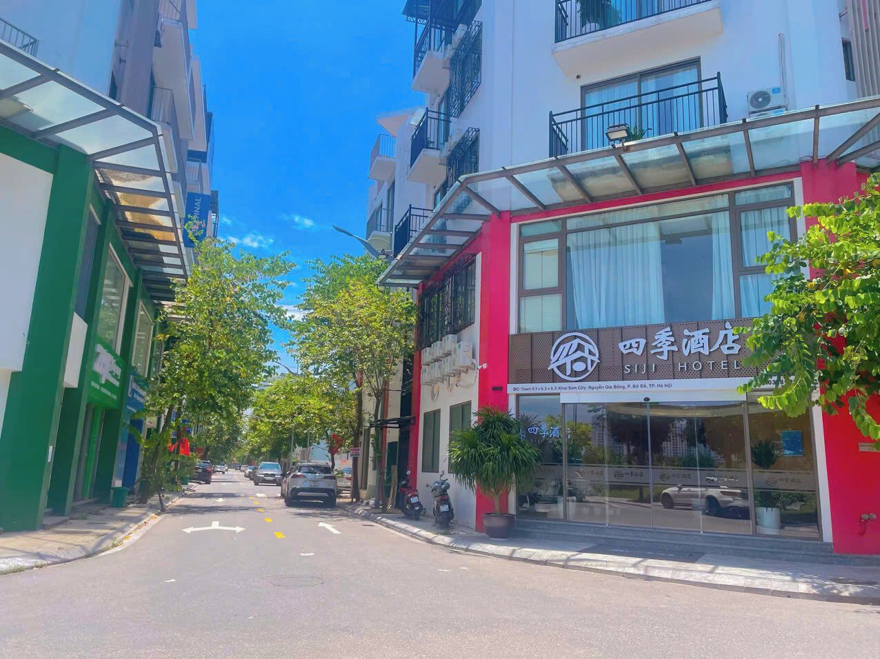 A hotel with a glass facade, a red awning, and a sign in a foreign language.