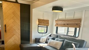 A cozy RV interior with a sofa, a dining table, and a chair.