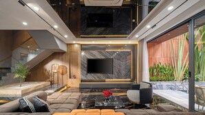 A modern living room with a large flat-screen TV, a marble floor, and a sofa with orange cushions. - Vidanang Luxury Villa - 6 Bedrooms - Pool - Sauna - Karaoke (Đà Nẵng)