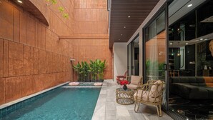 A modern indoor pool area with a clear pool, wooden walls, and a seating area with wicker chairs and a sofa. - Vidanang Luxury Villa - 6 Bedrooms - Pool - Sauna - Karaoke (Đà Nẵng)