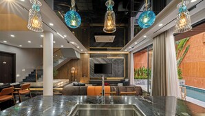 A modern interior with a marble countertop, stainless steel sink, and hanging blue glass pendant lights. - Vidanang Luxury Villa - 6 Bedrooms - Pool - Sauna - Karaoke (Đà Nẵng)