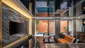 A modern living room with a large flat-screen TV, a sofa, and a coffee table. - Vidanang Luxury Villa - 6 Bedrooms - Pool - Sauna - Karaoke (Đà Nẵng)