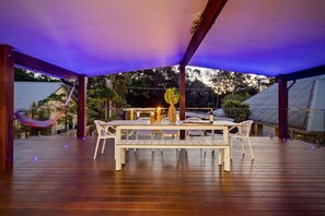 An outdoor patio with a table set for dining, surrounded by chairs, under a canopy. - The Perrins Lane Compound - Reset, Relax, Enjoy! (Arakoon)