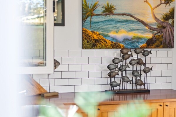 A kitchen with white subway tiles, a wooden countertop, and a decorative fish sculpture.
