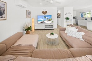 Un salón moderno con un sofá, una mesa de centro y un televisor que muestra una escena de playa.
