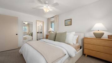 A bedroom with a bed, bedside table, lamp, and a ceiling fan.