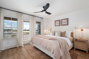 A bedroom with a bed, two bedside tables, a ceiling fan, and a window with curtains. - New Beachside Home! Pool & Pet Friendly! (Kill Devil Hills)