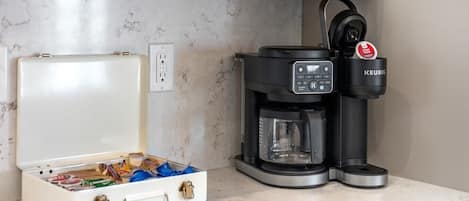 A coffee maker with a Keurig brand, a white travel case with compartments, and a marble countertop.