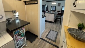 A laundry area with a washing machine, a drying rack, and a shelf with a potted plant. - Spacious Country Getaway (Guilford)