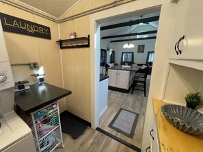 A laundry area with a washing machine, a drying rack, and a shelf with a potted plant.