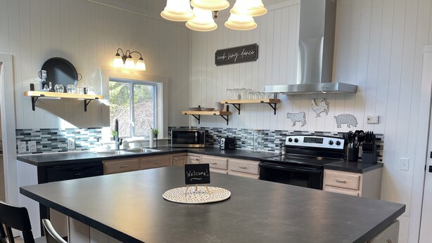 A modern kitchen with a central island, stainless steel appliances, and a 'Welcome!' sign. - Spacious Country Getaway (Guilford)