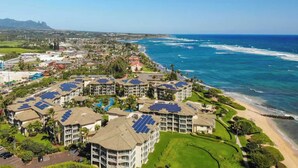Een kustresort met meerdere gebouwen, zonnepanelen, een strand en een golfbaan.