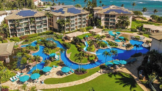 Een resort met meerdere zwembaden, een groot uitzicht op de oceaan en zonnepanelen op de gebouwen.