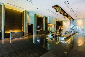 Eine moderne Lobby mit einer Rezeption, einer Sitzecke und einer großen Glaswand.