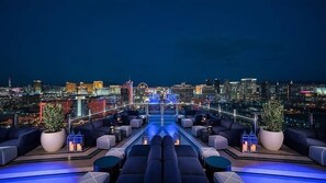 Eine Dachterrasse mit Blick auf die Stadt, ausgestattet mit Sofas, Topfpflanzen und einem Pool.