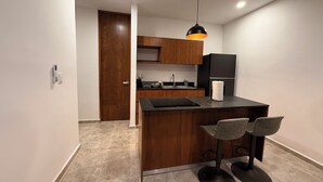 A compact kitchen with a wooden countertop, a black refrigerator, and a pendant light. - Luxe Apt. in Montebello Pool/Game Room/ Workspace (Mérida)