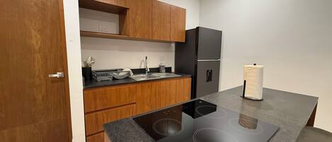 A modern kitchen with wooden cabinets, a black refrigerator, and a built-in stove.