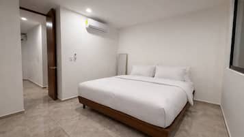 Un dormitorio con cama, una puerta, unidad de aire acondicionado y ventana.