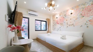A bedroom with a bed, a TV, a wall-mounted air conditioner, a ceiling light fixture, and a floral mural. - The Pivot Suite Ben Thanh - District 1 (Ho Chi Minh City)