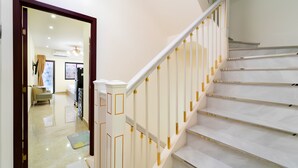 A staircase with white steps and gold accents, leading to a room with a beige sofa and a rug. - The Pivot Suite Ben Thanh - District 1 (Ho Chi Minh City)