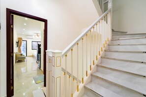 A staircase with white steps and gold accents, leading to a room with a beige sofa and a rug.