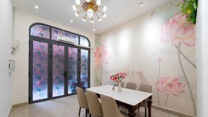 A dining area with a table and chairs, a decorative vase with flowers, and a wall mural of flowers. - The Pivot Suite Ben Thanh - District 1 (Ho Chi Minh City)