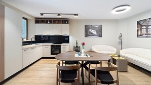 A modern kitchen with built-in appliances, a dining area with a round table and chairs, and a living area with a sofa and artwork. - Dariocchi by Interhome (Poreč/Kaštelir)