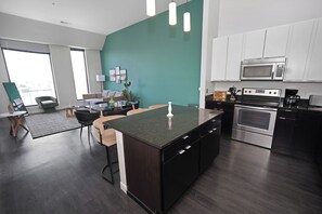 A modern kitchen with dark wood cabinetry, a central island, and a dining area with chairs and a table.