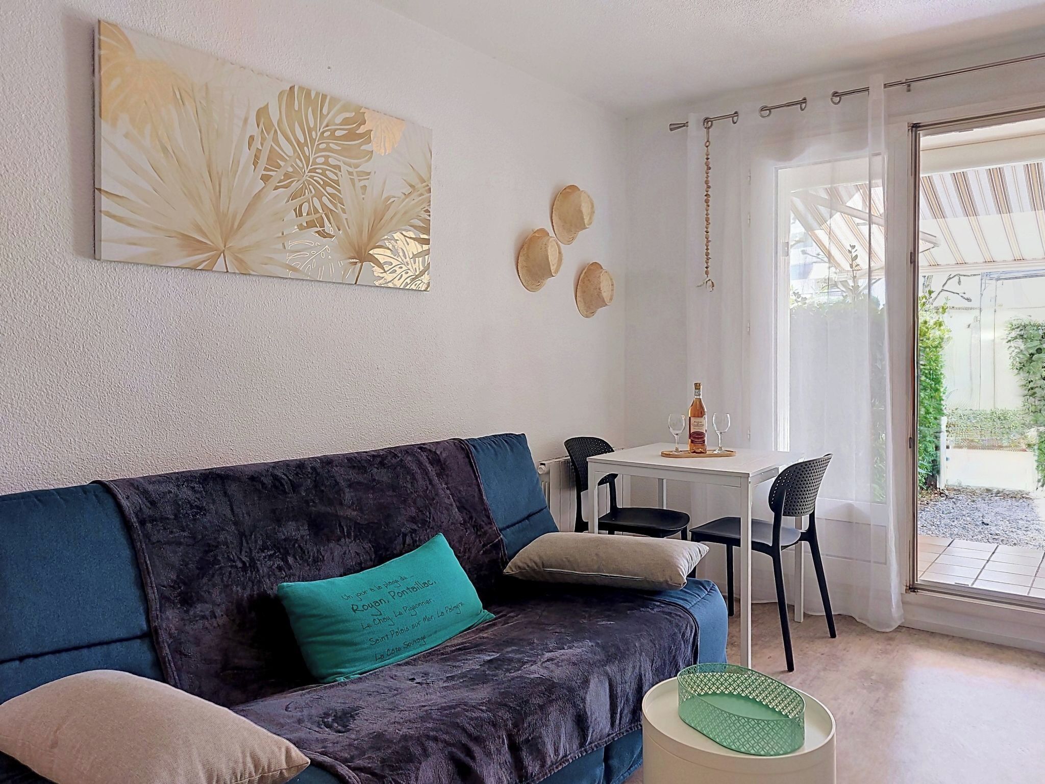 A cozy living area with a dark blue sofa, a green cushion, and a table with a bottle and glasses.