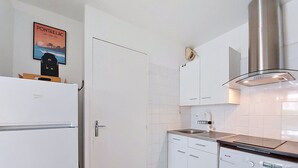 A compact kitchen with a built-in washing machine, a stainless steel range hood, and white cabinetry. - Les Jardins de l'Océan by Interhome (Vaux Sur Mer)