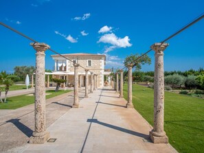 A courtyard with stone columns, a building with a tiled roof, and a clear blue sky. - Villa mit Jacuzzi by Interhome (Selva)