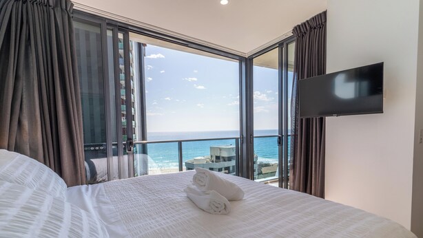 Ein Hotelzimmer mit einem großen Bett, einem Flachbildfernseher und Blick auf den Ozean.