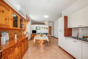 Eine Küche mit Holzausstattung, einem Esstisch mit Stühlen, einem Fernseher und einem Kühlschrank.