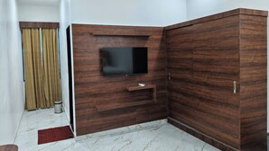 Kulmassa sijaitseva huone, jossa on seinälle asennettu televisio, puupaneeliseinä, vaatekaappi ja marmorilattia.