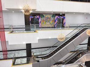 Espacio interior con escaleras mecánicas, barandillas de vidrio e iluminación decorativa.