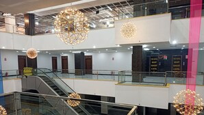 Monitasoinen hotellin sisustus, jossa on liukukäytäviä, suuria kattokruunuja ja opasteita, jotka kertovat, että kyseessä on Royal Height Banquet & Hotel.