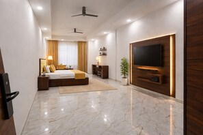 A modern hotel room with a large bed, a flat-screen TV, a ceiling fan, and a marble floor.