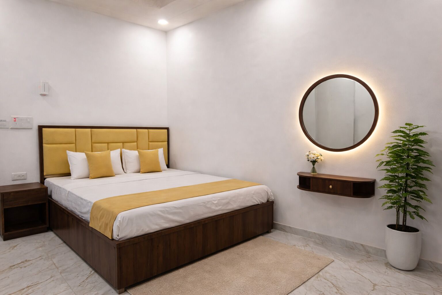 A modern hotel room with a wooden bed, a bedside table, a nightstand, a wall-mounted mirror, and a potted plant.