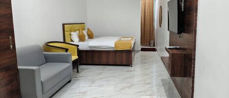 A hotel room with a bed, a sofa, a television, and a marble floor.
