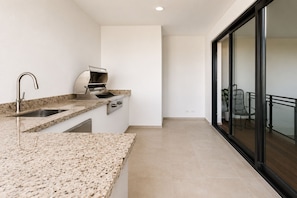 Eine moderne Küche mit Granit Arbeitsplatten, einem eingebauten Backofen und einem Spülbecken.