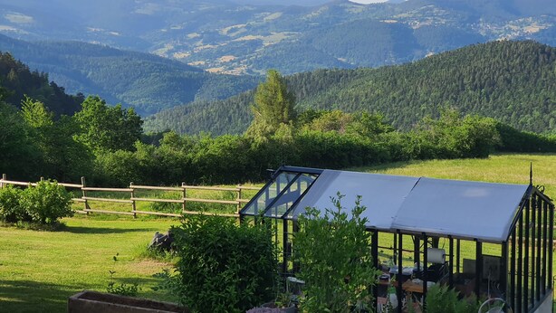 A greenhouse with a transparent roof, surrounded by a wooden fence, set against a backdrop of rolling hills and a clear sky. - Room in the heart of the Vosges Mountains, near the Petit Ballon (Breitenbach-Haut-Rhin)