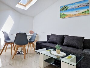 A modern living room with a glass coffee table, a dark sofa, and a dining area with chairs and a table. - Mary & Klara by Interhome (Trogir/Okrug Gornji)