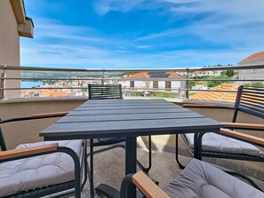 A balcony with a table and chairs, overlooking a cityscape and water. - Mary & Klara by Interhome (Trogir/Okrug Gornji)