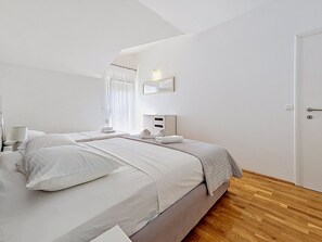 Een hotelkamer met twee bedden, een nachtkastje met lamp, een spiegel en een deur.