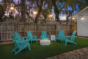 A backyard with a wooden fence, a white building, and turquoise Adirondack chairs arranged around a central fire pit. - NEW! Okaloosa Island, Destin, Navarre
3 bedroom/ 2 bath, pool, beach gear (Mary Esther)