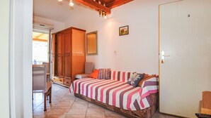 Una habitación con techo de madera, una cama con ropa de cama a rayas, un armario de madera y una puerta con un número.