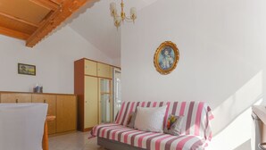 A room with a sofa, a wooden cabinet, a dining table, and a chandelier. - Apartment Jako by Interhome (Trogir/Slatine)