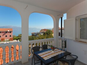 Ein Balkon mit Tisch, Stühlen und Blick auf das Meer und Gebäude.