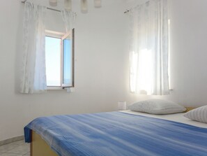 Ein Schlafzimmer mit Bett, Vorhängen, einem Fenster und einer Wandleuchte.