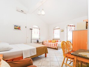 Ein Zimmer mit zwei Betten, einem Schreibtisch, einem Stuhl und einem Fenster mit Vorhängen.